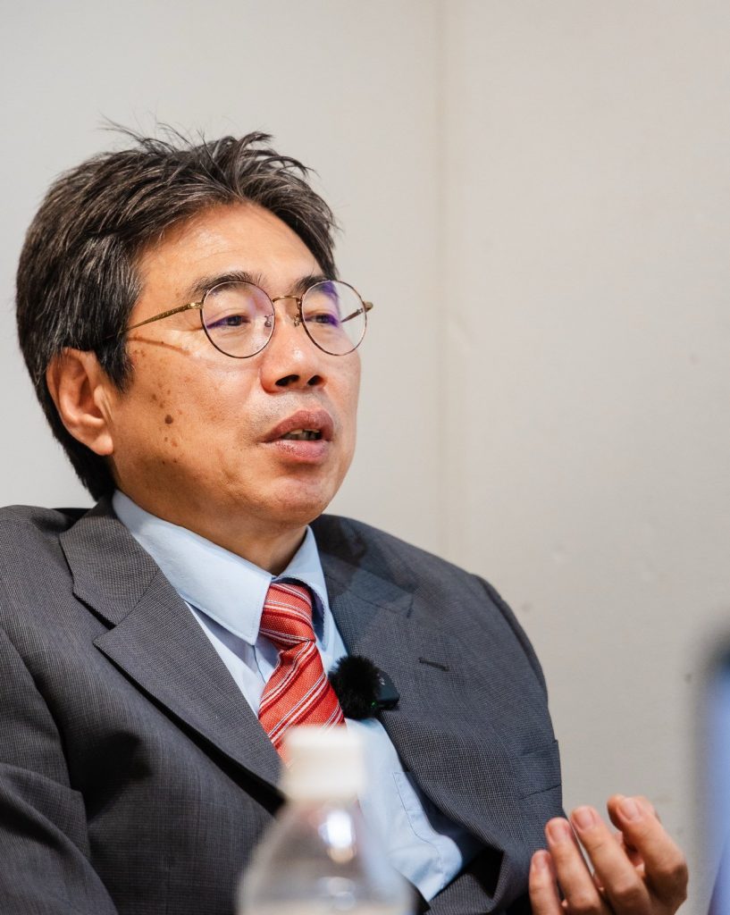 椅子に腰かけ、身ぶりを交えて話す坂本浩則社長
