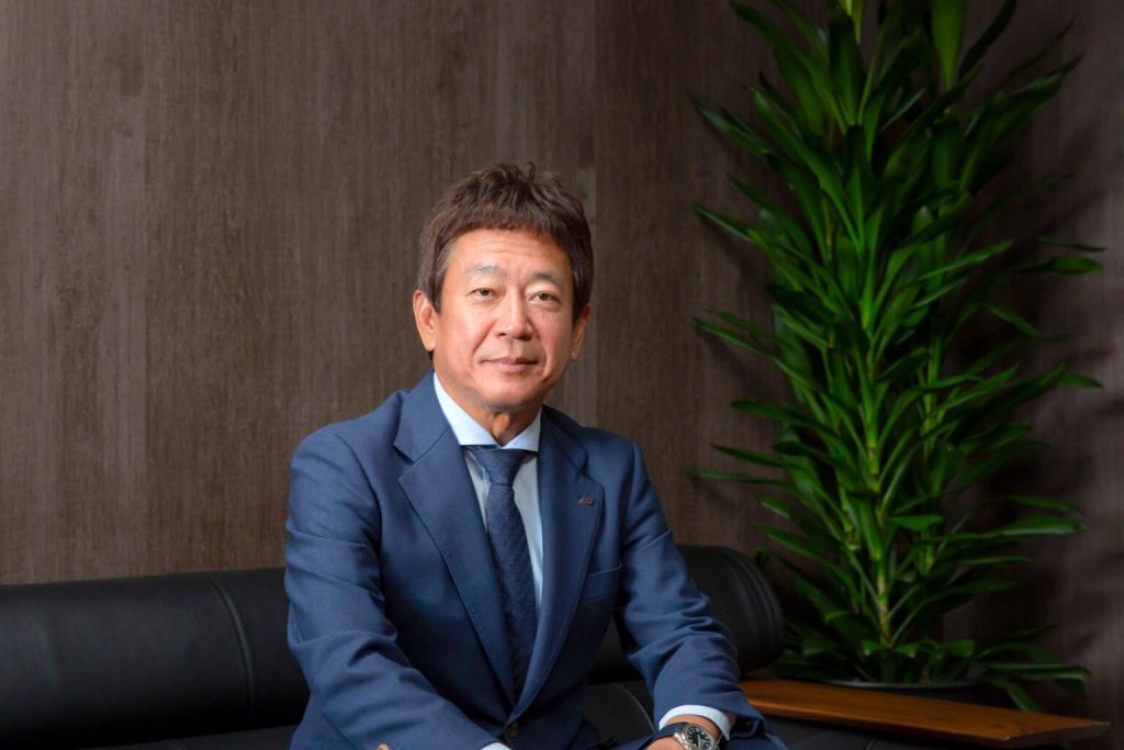 応接室のソファに腰かけ、正面を向く末廣󠄁社長